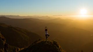 Woman doing yoga stance on top of a mountain